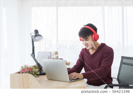 Man using laptop and has headphone on his neck.. 56421396