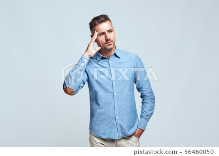 Lost in thoughts. Portrait of young and smart bearded man in casual wear touching his head and 56460050