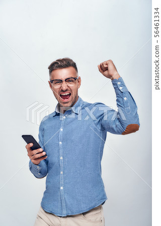 Success Portrait of handsome and happy bearded man in eyewear holding smart phone and keeping one Success Portrait of handsome and happy bearded man in eyewear holding smart phone and keeping one 56461334