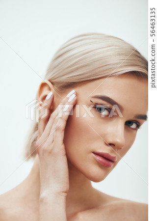Pretty and young blonde woman touching her face with black surgical lines on eyelids and looking at Pretty and young blonde woman touching her face with black surgical lines on eyelids and looking at 56463135