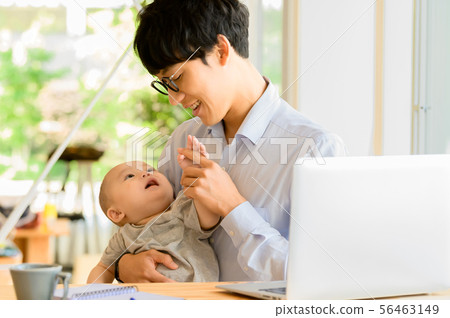 在抱孩子的同時工作的男人 在抱孩子的同時工作的男人 56463149