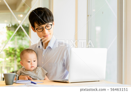 在抱孩子的同時工作的男人 56463151