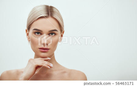 Perforation lines. Beautiful and young blonde woman with black surgical lines on eyelids and under 56463171