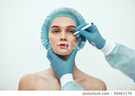 Perfect face. Beautiful and young woman in blue medical hat waiting for facial surgery while plastic Perfect face. Beautiful and young woman in blue medical hat waiting for facial surgery while plastic 56463176