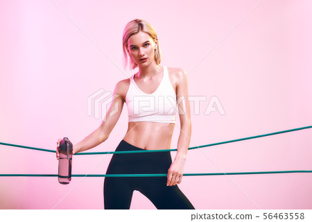 Fitness girl. Sporty young woman in white top and black leggings holding bottle of water and working Fitness girl. Sporty young woman in white top and black leggings holding bottle of water and working 56463558