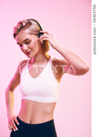 Music making me happy. Cute and sporty woman adjusting headphones and keeping eyes closed while Music making me happy. Cute and sporty woman adjusting headphones and keeping eyes closed while 56463700