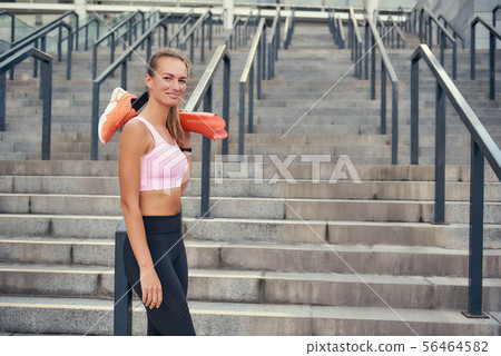 Never give up Happy smiling woman in sports clothing holding her leg prosthesis while standing 56464582