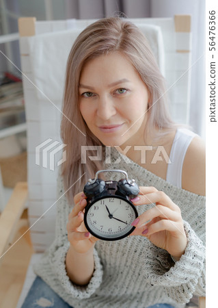 Blonde young woman holding a black clock Blonde young woman holding a black clock 56476366