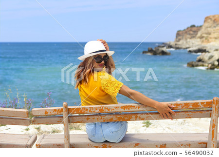 Pretty young woman in a straw hat sitting on a Pretty young woman in a straw hat sitting on a 56490032