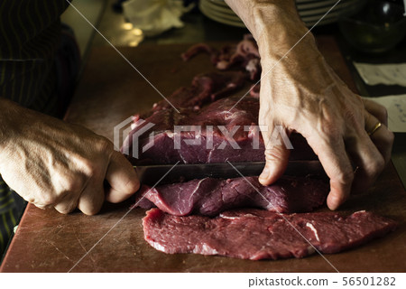 man cutting a piece of beef in a professional man cutting a piece of beef in a professional 56501282