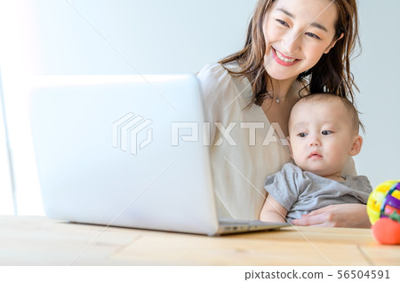 A woman who operates a computer while holding a child 56504591