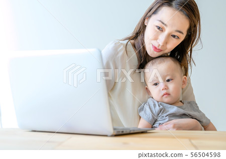 在抱孩子的同時操作電腦的女人 56504598