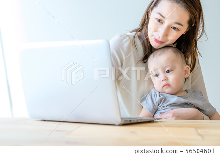 在抱孩子的同時操作電腦的女人 在抱孩子的同時操作電腦的女人 56504601