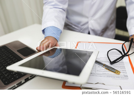 Doctor working with tablet computer at desk. Doctor working with tablet computer at desk. 56516591