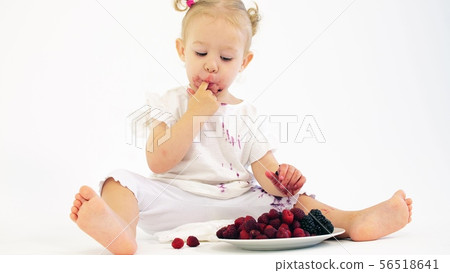 Blonde baby girl eating berries against white background Blonde baby girl eating berries against white background 56518641