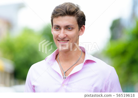 Face of happy young handsome businessman thinking outdoors Face of happy young handsome businessman thinking outdoors 56519618