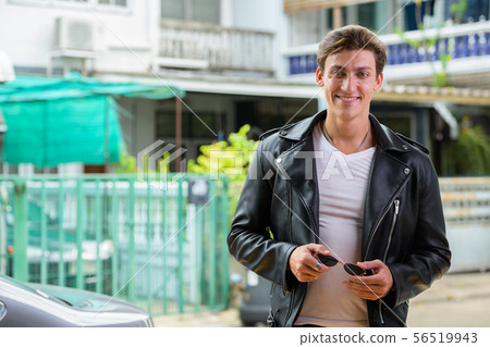 Happy young handsome rebellious man smiling outdoors Happy young handsome rebellious man smiling outdoors 56519943