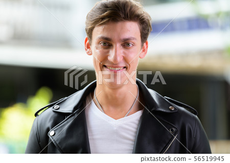 Face of happy young handsome rebellious man smiling outdoors Face of happy young handsome rebellious man smiling outdoors 56519945