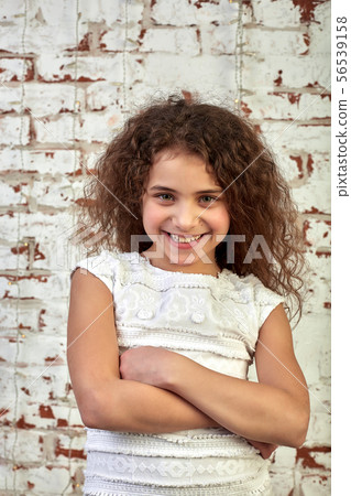 Young joyful girl smiling shyly over a brick wall crossed her arms relaxed Young joyful girl smiling shyly over a brick wall crossed her arms relaxed 56539158