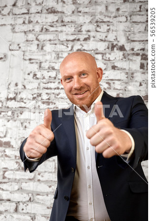 Successful male bald businessman poses for the camera and shows class with his hands. Successful 56539205
