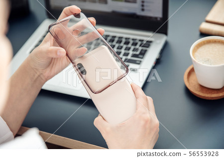 Woman's hands put silicone case on the back side 56553928
