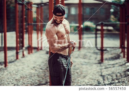 Fitness man exercising with stretching band in outdoor gym. Fitness man exercising with stretching band in outdoor gym. 56557450