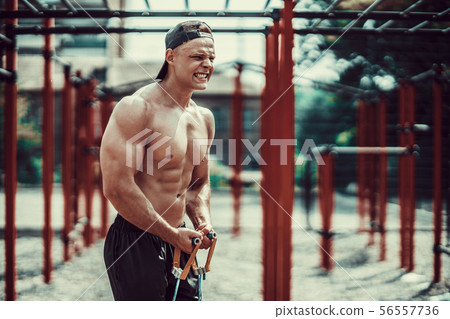 Fitness man exercising with stretching band in outdoor gym. Fitness man exercising with stretching band in outdoor gym. 56557736
