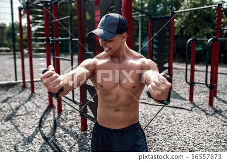 Fitness man exercising with stretching band in outdoor gym. Fitness man exercising with stretching band in outdoor gym. 56557873