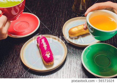 Glazed Cherry eclair on white dish topped with chocolate scribble candy served with a side of 56571024