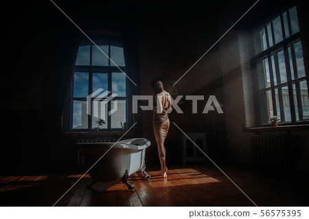 Women in dress standing in old decorated room with bath 56575395