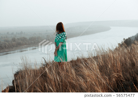 Young women in dress on slope by river 56575477