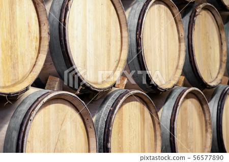 Wooden wine oak barrels stacked in straight rows Wooden wine oak barrels stacked in straight rows 56577890