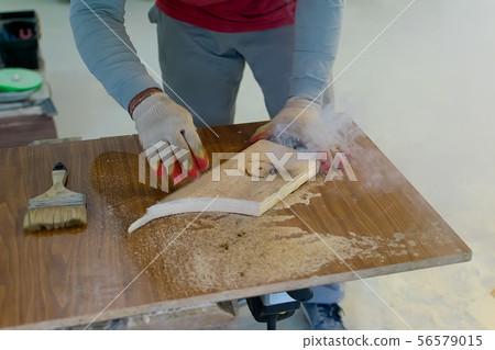 Hands of the master in gloves hold a wooden billet Hands of the master in gloves hold a wooden billet 56579015