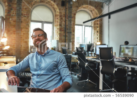 Smart and successful. Portrait of happy young bearded man in eyeglasses and headphones smiling while Smart and successful. Portrait of happy young bearded man in eyeglasses and headphones smiling while 56589090
