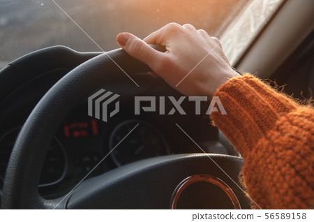 Close-up of a female hand in an orange sweater driving a car outside the city. Slow motion Woman Close-up of a female hand in an orange sweater driving a car outside the city. Slow motion Woman 56589158