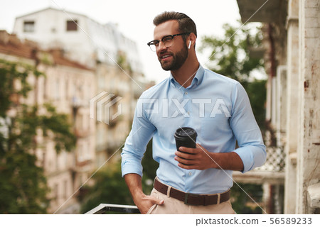 Nice talk. Young and handsome bearded man in eyeglasses and headphones holding cup of coffee and Nice talk. Young and handsome bearded man in eyeglasses and headphones holding cup of coffee and 56589233