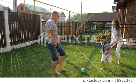 parents enjoy life playing football with active boy on lawn parents enjoy life playing football with active boy on lawn 56591375