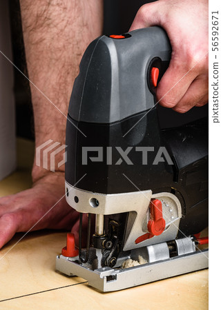 Man with electric jig saw cutting wood Man with electric jig saw cutting wood 56592671