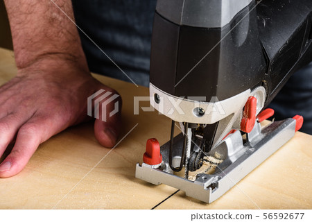 Man with electric jig saw cutting wood 56592677