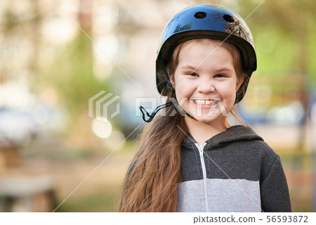 Little girl in a helmet smiling funny. 56593872