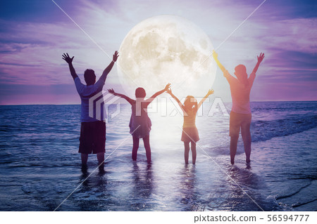 family standing on beach and watching the 56594777
