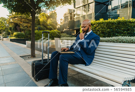 Indian businessman holding laptop notebook wearing blue suit near office Indian businessman holding laptop notebook wearing blue suit near office 56594985