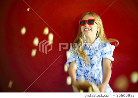 Little girl wearing sunglasses and eating popcorn Little girl wearing sunglasses and eating popcorn 56606952