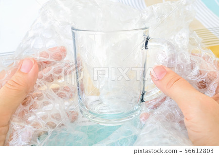 Woman hands package glass tea cup with bubble wrap 56612803