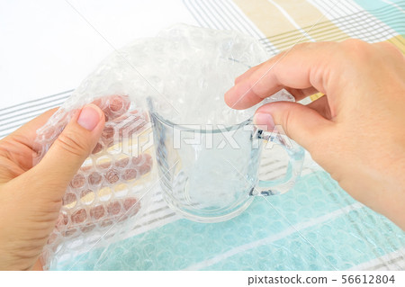Woman hands package glass tea cup with bubble wrap 56612804