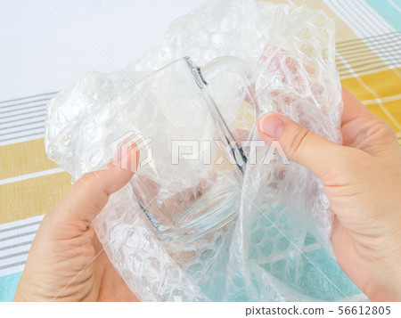 Woman hands package glass tea cup with bubble wrap 56612805
