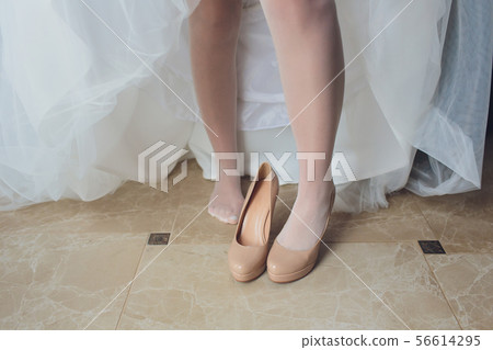 Bride in a beautiful wedding dress putting on shoes. Bride in a beautiful wedding dress putting on shoes. 56614295