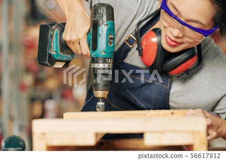 Carpenter using electric drill 56617812