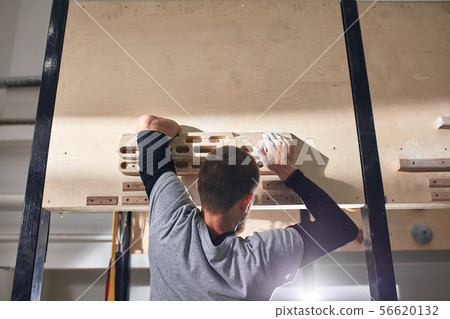 Young rock climber without forearm hanging on special wooden panel Young rock climber without forearm hanging on special wooden panel 56620132