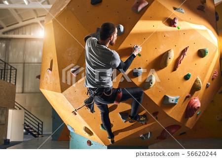 Unrecognizable sportsman without forearm rock-climbing at yellow wall 56620244